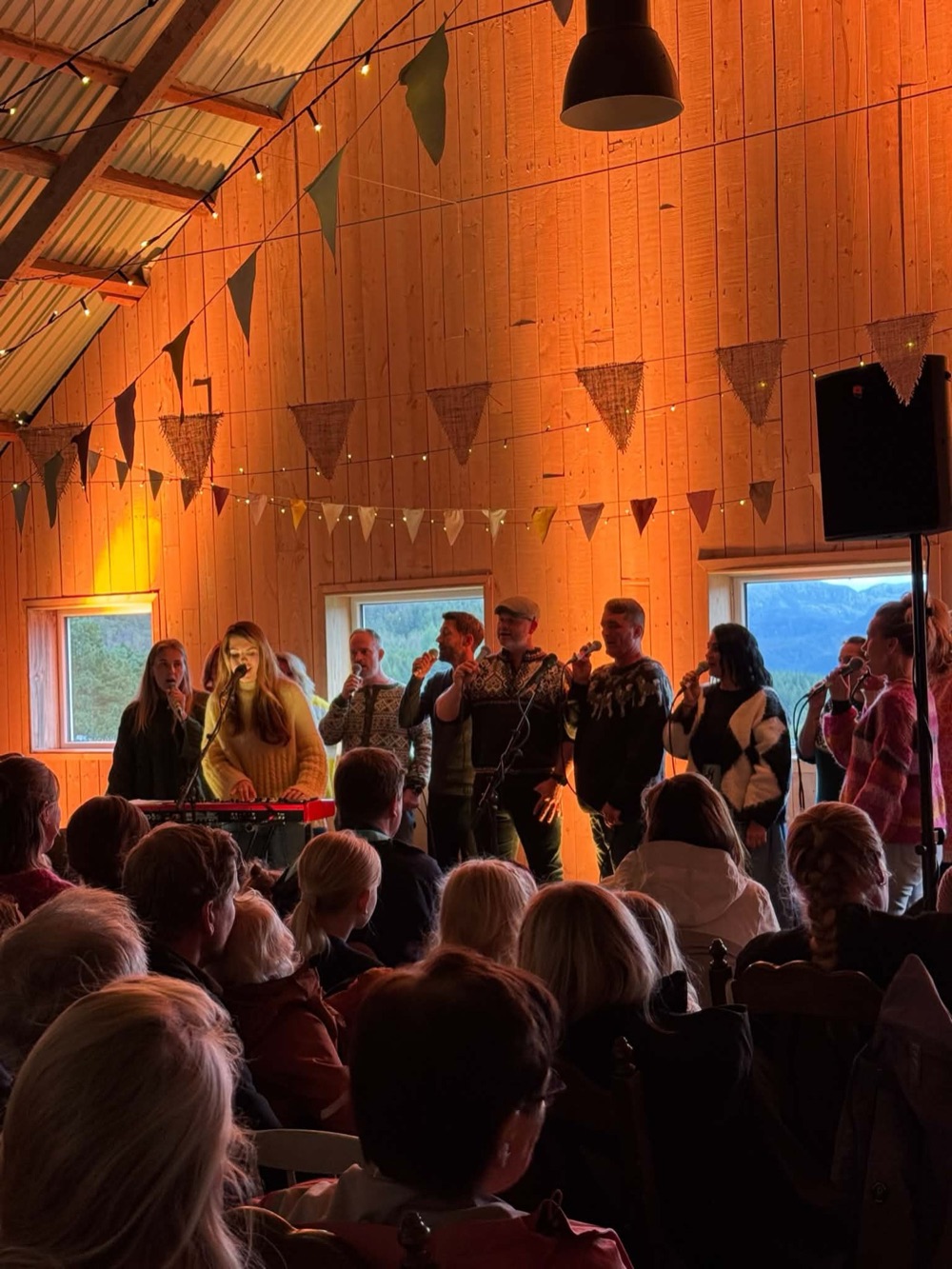 Publikum samlet til konsert under et varmt belyst tretak